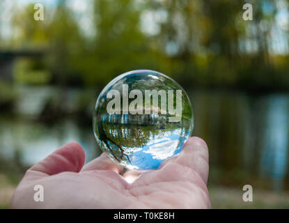 Une personne méconnaissable avec une boule de cristal dans sa main avec un reflet du paysage Banque D'Images