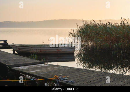 Peu pier avec bateau sur le lac au début matin brumeux. Banque D'Images