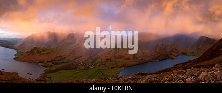 Une douche passe au-dessus de Crummock Water, Grasmoor Rannerdale Whiteless, noeuds, Pike et Buttermere village, produisant un arc-en-ciel vif. Lake District, UK Banque D'Images