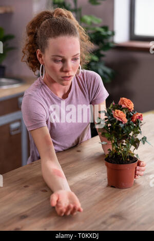 Curly malheureux femme allergique on plant Banque D'Images