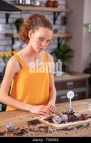 Bouleversé bon-à la femme assise dans la cuisine et à la recherche sur le chocolat Banque D'Images