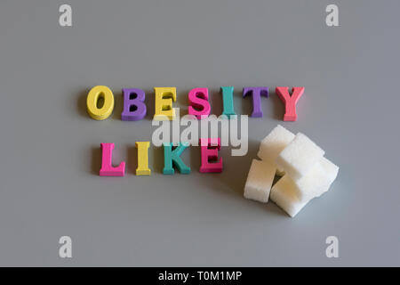 Le concept de l'obésité. L'inscription sur un fond gris l'obésité comme le sucre. Banque D'Images