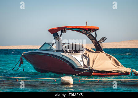 Motor Yacht de luxe rouge élégante sur l'arrière-plan de la mer bleu azur et une bande de plage de montagnes en arrière-plan Banque D'Images