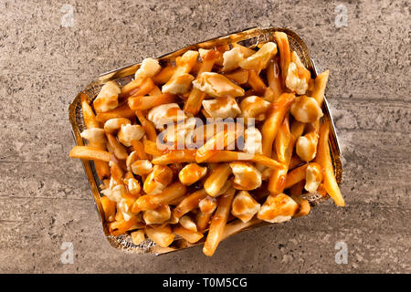 La poutine dans un récipient pour emporter. Cuite avec des frites, du fromage en grains et sauce au boeuf. Une cuisine canadienne. Banque D'Images