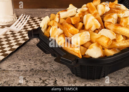 La poutine dans un récipient pour emporter. Cuite avec des frites, du fromage en grains et sauce au boeuf. Une cuisine canadienne. Banque D'Images