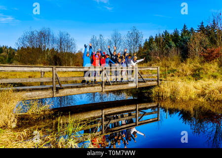 Trois générations d'une famille en train d'encourager un pont sur les sentiers des terres humides du ruisseau Silverdale, un marais d'eau douce et marais près de Mission, C.-B. Banque D'Images