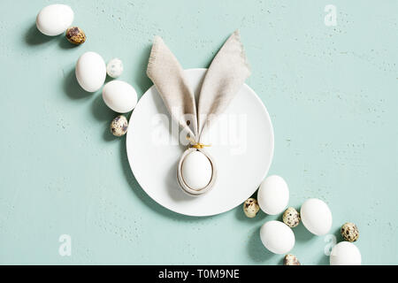 Poulet et oeufs de cailles avec oreilles de lapin de linge serviette sur la table, texturé bleu composition Pâques, vue du dessus Banque D'Images