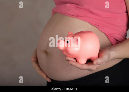 Les jeunes femmes enceintes entre 30 et 35 ans femme garde pink piggy bank. Libre Banque D'Images