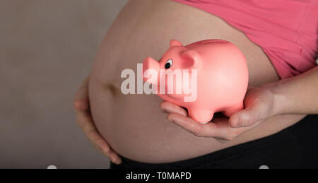 Les jeunes femmes enceintes entre 30 et 35 ans femme garde pink piggy bank. Libre Banque D'Images