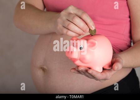 Les jeunes femmes enceintes entre 30 et 35 ans femme garde pink piggy bank. Libre Banque D'Images