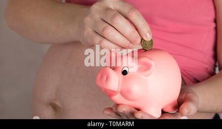 Les jeunes femmes enceintes entre 30 et 35 ans femme garde pink piggy bank. Libre Banque D'Images