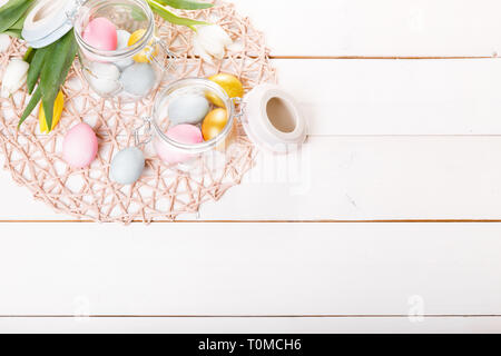 Arrière-plan de pâques avec rose, bleu, golden oeufs de Pâques dans un bocal en verre sur un bureau en bois blanc Banque D'Images