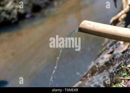 L'eau du tube de bambou se jette dans la rivière de l'île de Ubud, Bali, Indonésie. Close up Banque D'Images