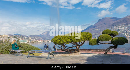 Lugano, Suisse - 10 mars 2019 : une femme assise sur un banc sur la promenade, le lac de Lugano, Tessin, Suisse Banque D'Images