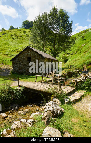 Chalet en pierre borda et pont en bois près de la grotte ARPEA, spectaculaire pli anticlinal entouré de pâturages verts dans les Pyrénées françaises (Estérençuby, France) Banque D'Images