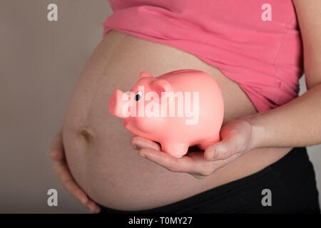 Les jeunes femmes enceintes entre 30 et 35 ans femme garde pink piggy bank. Libre Banque D'Images