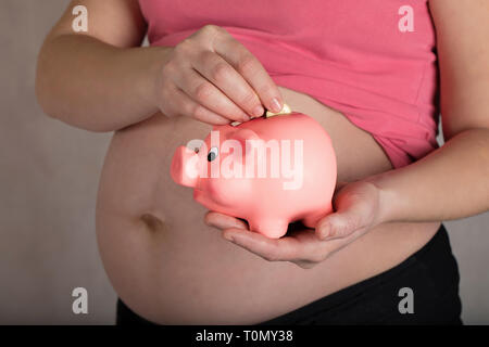 Les jeunes femmes enceintes entre 30 et 35 ans femme garde pink piggy bank. Libre Banque D'Images