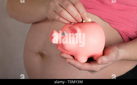 Les jeunes femmes enceintes entre 30 et 35 ans femme garde pink piggy bank. Libre Banque D'Images