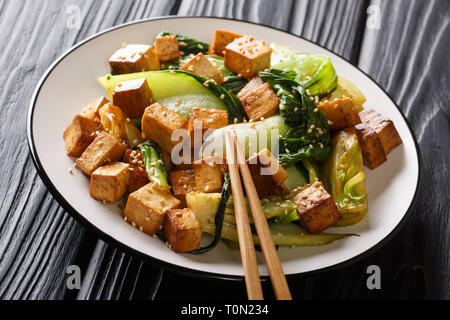 Veggie tofu frit avec petits bok choy, la sauce soja et les graines de sésame gros plan sur une assiette sur la table horizontale. Banque D'Images