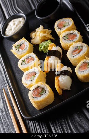 Tamagoyaki Set sushi roll avec du riz, du fromage, du saumon et d'avocat libre sur une plaque verticale sur la table. Banque D'Images