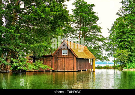 Ancien hangar à bateaux en bois avec petite fenêtre sous les arbres à Schweriner See. Mecklenburg-Vorpommern Allemagne Banque D'Images