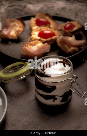 Photo verticale de petit pot de verre avec couvercle hermétique. Jar est pleine de sauce blanche. Sauce brune foncé sont déversés dans un blanc. Pot est placé sur un boa Banque D'Images