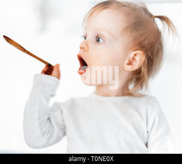 Cute little girl nourrir sa soeur avec une cuillère. L'amour familial et les soins concept. Banque D'Images