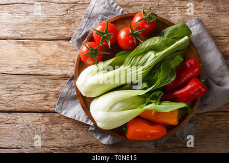 Des ingrédients frais petits bok choy, les tomates et les poivrons sur une plaque sur une table en bois. Haut horizontale Vue de dessus Banque D'Images