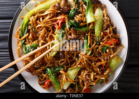 Les sautés de nouilles Udon avec pak choi et les champignons shiitake close-up sur une assiette. Haut horizontale Vue de dessus Banque D'Images