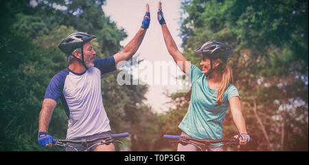 Athletic couple giving high five tout en vélo sur la route Banque D'Images