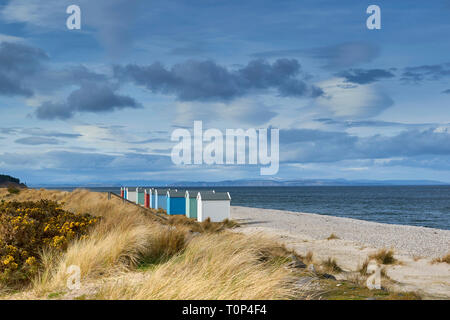 MORAY ECOSSE FINDHORN BEACH CHALETS colorés ou des cabanes de plage sur la plage de galets de la NEIGE SUR LES COLLINES ET BLACK ISLE Banque D'Images