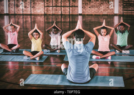 Les enfants de l'école et professeur de yoga au cours de méditation Banque D'Images