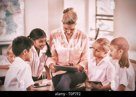 Enseignant d'enseigner aux enfants on digital tablet Banque D'Images