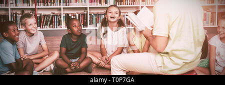 Enseignant d'enseigner aux enfants dans la bibliothèque Banque D'Images