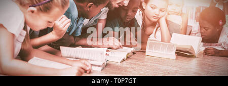 Enfants et enseignants lying on floor reading book in library Banque D'Images