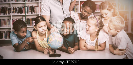 L'enseignant et les étudiants à la recherche à globe in library Banque D'Images