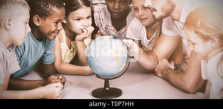 Les élèves et le professeur looking at globe in library Banque D'Images