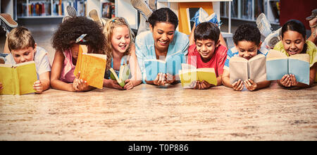 La lecture de livres avec les élèves de l'enseignant en position couchée Banque D'Images