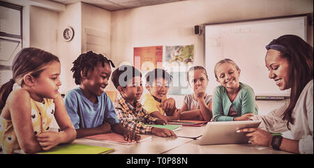 Smiling teacher with tablet computer leçon donner aux étudiants Banque D'Images