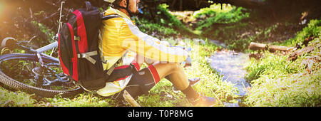 Mountain biker assis près de ruisseau et à la nature à Banque D'Images