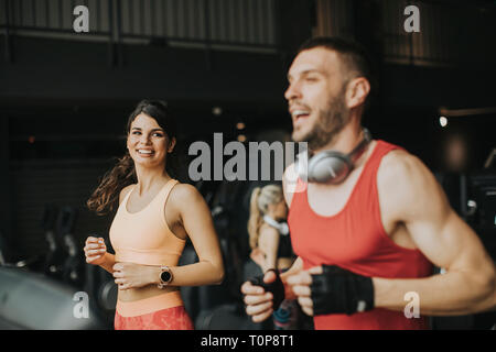 Jeune couple en marche sur des tapis roulants dans la salle de sport moderne Banque D'Images