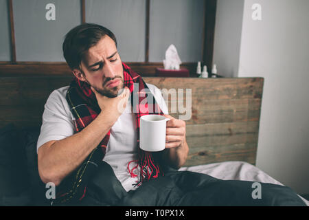 Photo d'un jeune homme avec un mouchoir. Guy malade réside dans lit et a le nez. l'homme fait un remède pour le rhume mâle modèle a une haute Banque D'Images