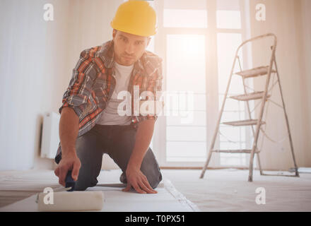 Fond d'accrochage des travailleurs . Le constructeur met la colle sur le papier peint. Banque D'Images