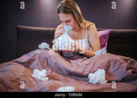 Photo de jeune femme à l'aide d'inhalateur pour la guérison. Elle inhale de l'air avec différents bonus. Femme assise sur le lit seul. Il y a beaucoup de blanc utilisé Banque D'Images