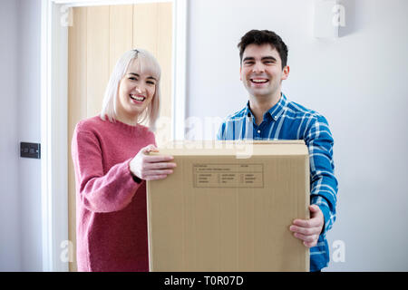 Portrait of Young Couple Carrying Cases dans nouvelle maison le jour du déménagement Banque D'Images