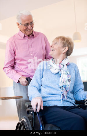 Senior Femme poussant en fauteuil roulant à la maison Banque D'Images