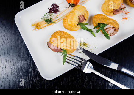 Mousse au fromage avec du bacon dans eclair, servi sur une assiette et couverts de vert et de tomate cherry Banque D'Images