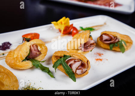 Mousse au fromage avec du bacon dans eclair, servi sur une assiette et couverts de vert et de tomate cherry Banque D'Images