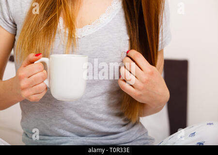 Woman relaxing at home confortable atmosphère sur le lit. Femme avec red nails manucure détient tasse de café en mains bénéficiant du confort Banque D'Images