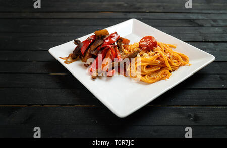 Les pâtes spaghetti fait maison avec de la viande de boeuf et légumes divers sur un tableau noir en bois. L'éclairage discret Banque D'Images